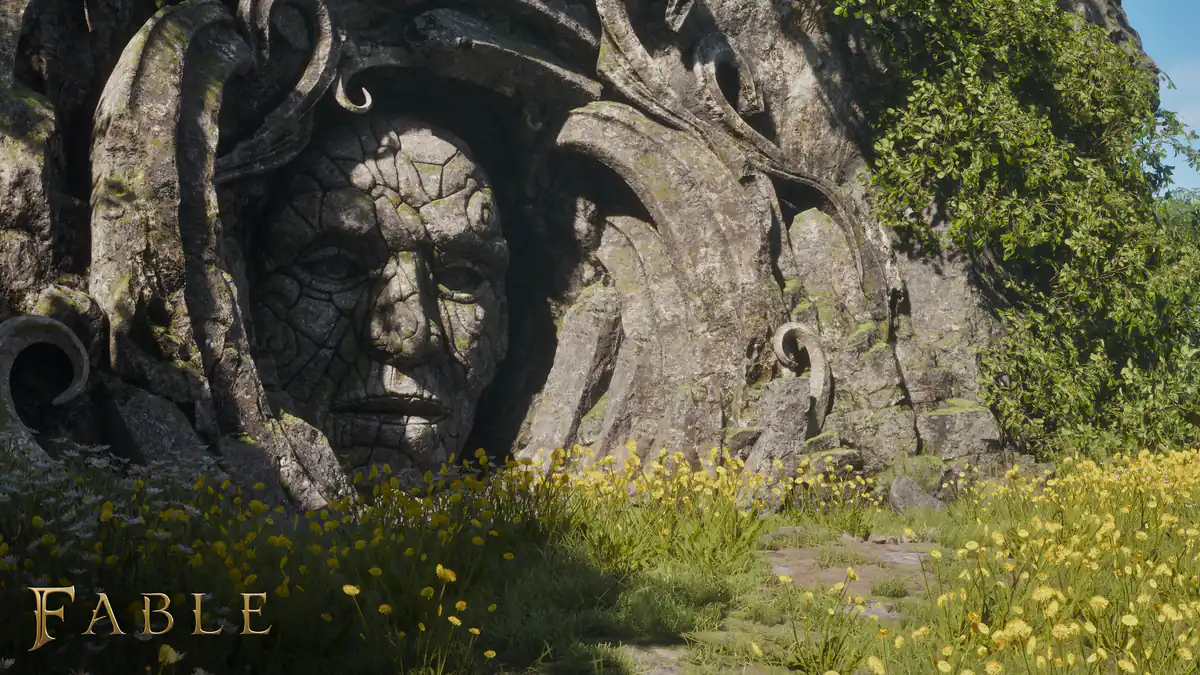 A huge stone face carved into a rock wall, above a meadow of yellow flowers