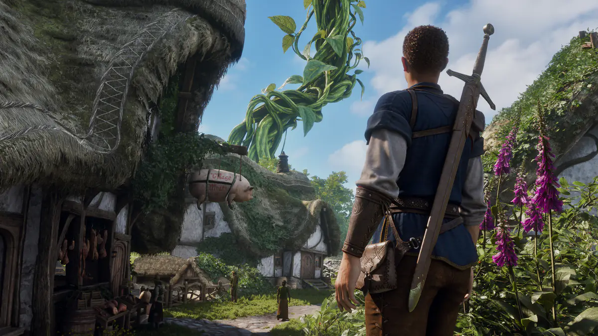 The Hero, a sword on his back, looks across a village of thatched houses toward a giant beanstalk